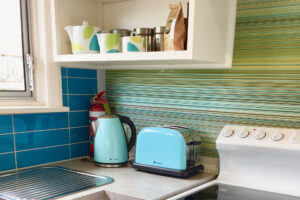 Corner of kitchen in a vacation rental accommodation showing teal jug and toaster with matching decor 